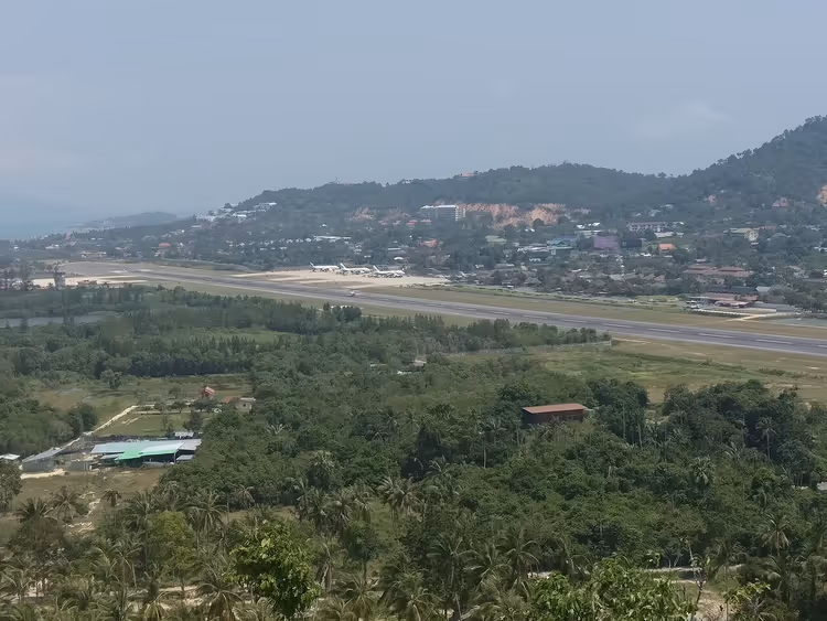 Rullebane på Samui lufthavn omgitt av tropiske palmer og åser
