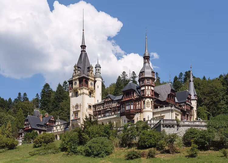 Peleș slott mot en bakgrunn av skog og himmel