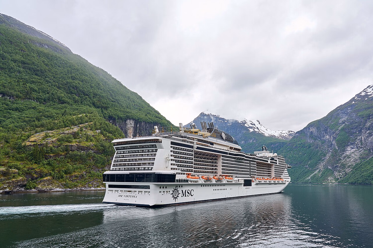 Cruiseskip som seiler gjennom Geirangerfjorden mellom fjellene