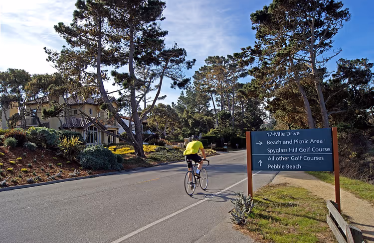 Syklist på 17-Mile Drive ved et skilt