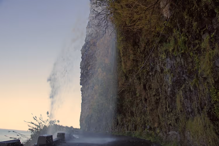Wasserfall Cascata dos Anjos, der auf die Straße am Meer stürzt