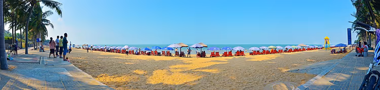 Strandpanorama met parasols, zand en palmbomen