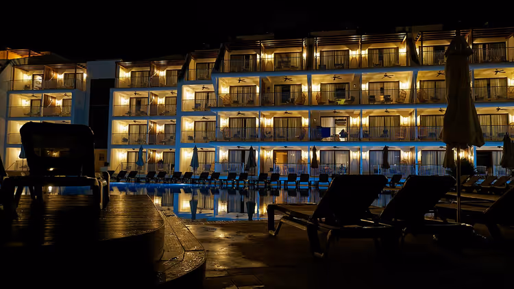 Hotelgebouw bij nacht met zwembad en ligstoelen
