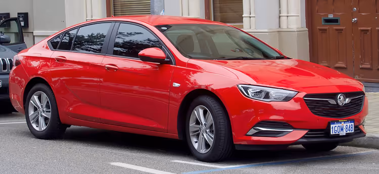 Kaldırımda park etmiş kırmızı Holden Commodore ZB sedan