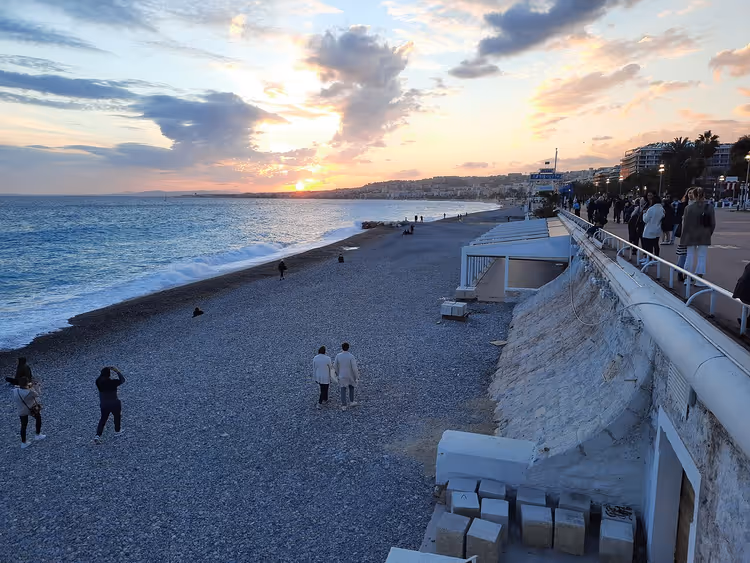 Kiezelstrand in Nice bij zonsondergang met mensen