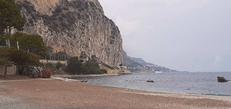 Yüksek bir kireçtaşı kayalığın altındaki çakıl plajı