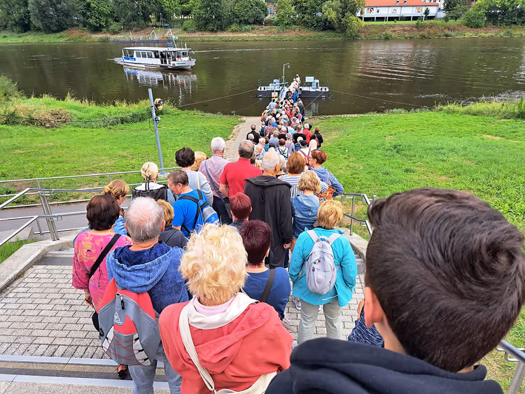 Touristen gehen in Bad Schandau zur Fähre hinunter