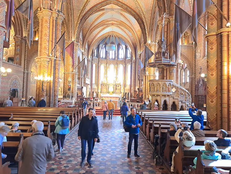 Interieur van de Matthiaskerk in Boedapest met kerkbanken en toeristen