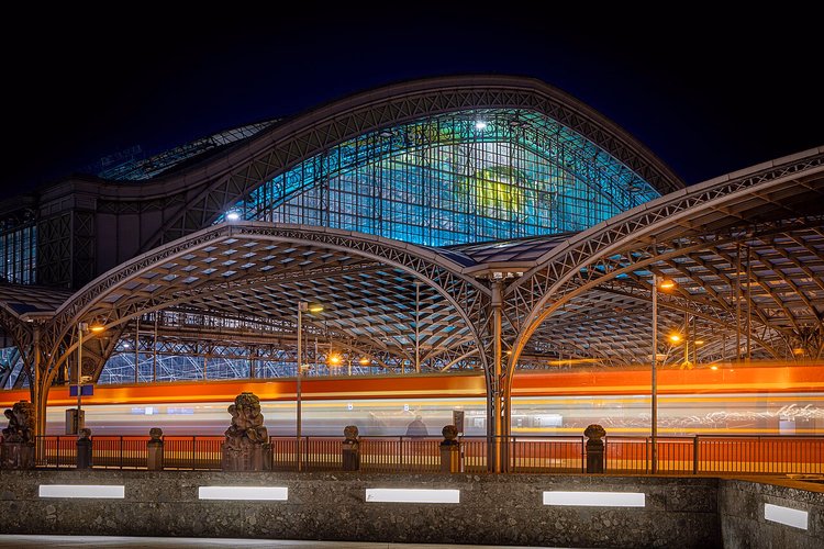 La estación de Colonia de noche con un tren pasando