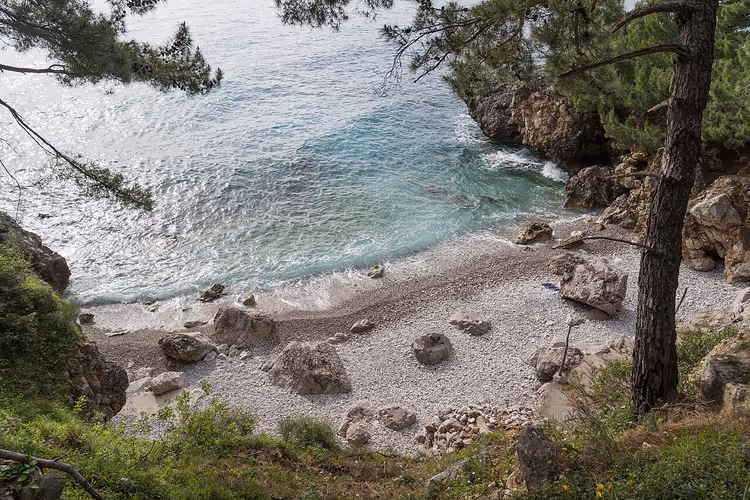 Kiezelstrand bij Kaap Ratac met dennenbomen