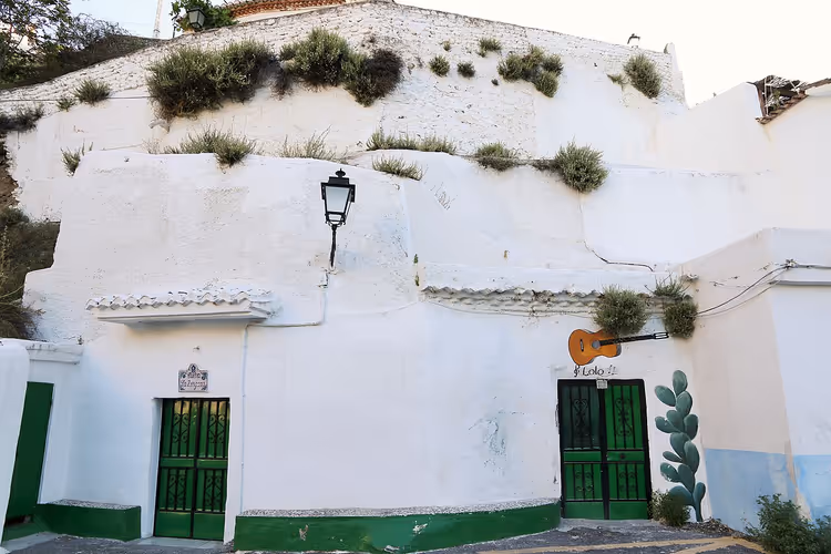 Vita grotthus i Sacromonte med gröna dörrar och en gitarr