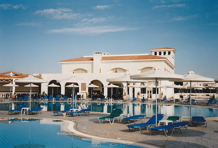 Otel havuzu ve şemsiyeli beyaz bina