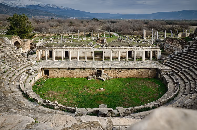 Ancient amphitheater, ruins and snow-covered mountains