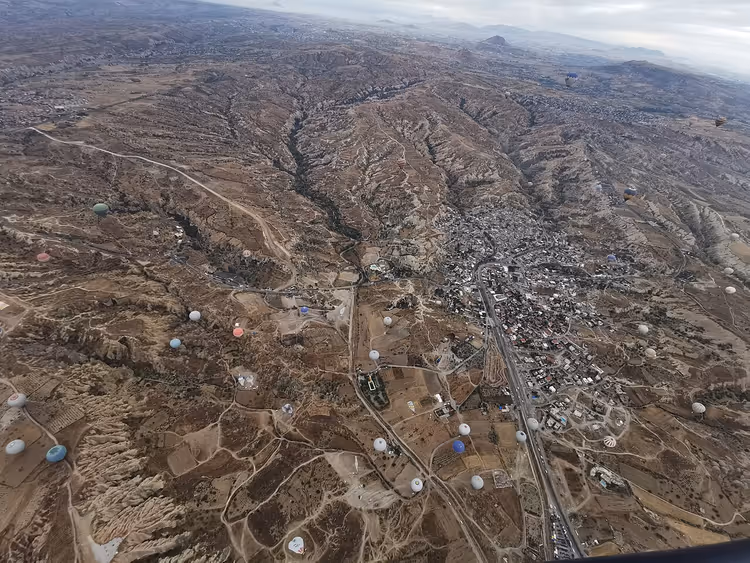 Kapadokya'da Göreme'nin vadileri ve kasabası üzerinden sıcak hava balonu manzarası