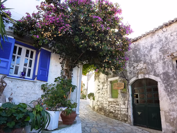 Steegje in Afionas met bougainville en blauwe luiken