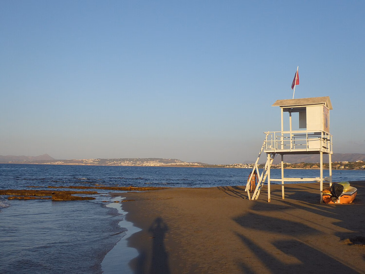 Strand von Agia Marina mit Rettungsschwimmerturm bei Sonnenuntergang