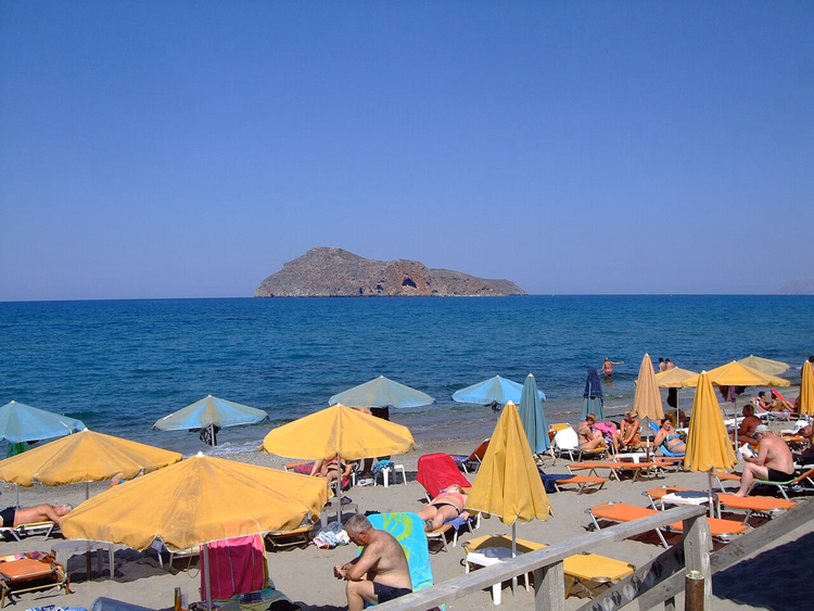 Strand met parasols tegenover het eiland Agioi Theodoroi