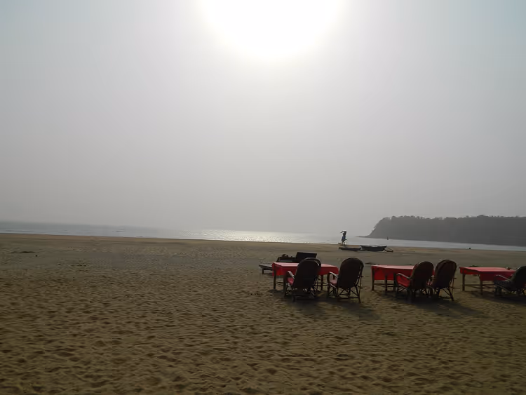 Zandstrand met rode tafels en stoelen aan zee