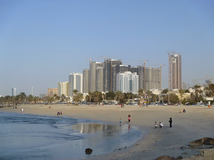 Sandstranden i Ajman med høyhus i bakgrunnen