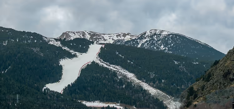 Pista da sci innevata tra montagne boscose
