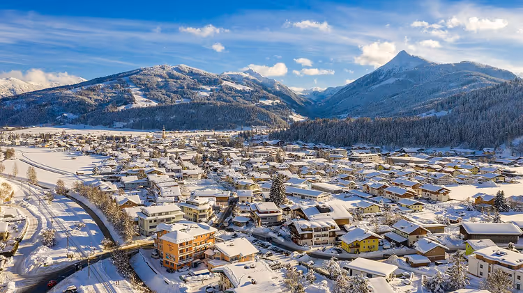 Vinterpanorama av en by i Alpene med snødekte fjell