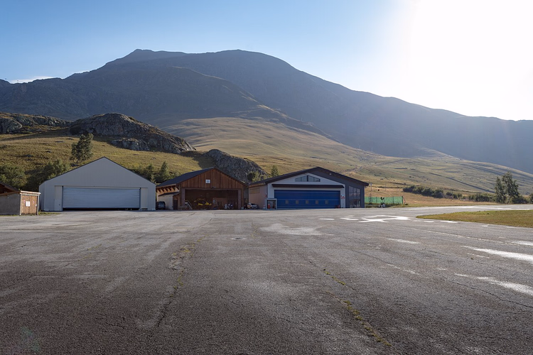 Hangars van het altiport van Alpe d'Huez met bergen op de achtergrond in de zomer