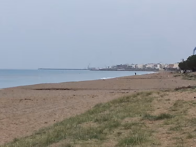 Zandstrand van Amoudara in de winter met uitzicht op het dorp