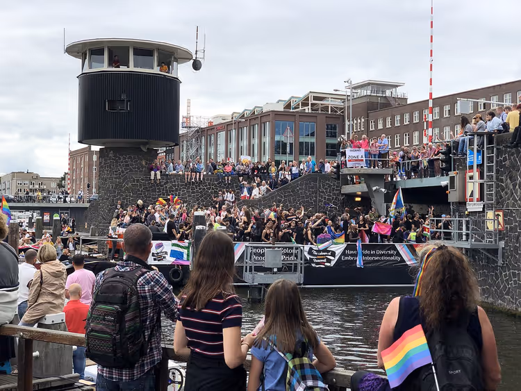 Toeschouwers en een boot bij een grachtenpride