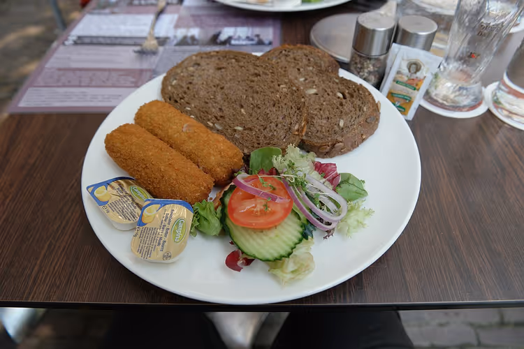 Zwei Kroketten mit Salat und Brot auf einem Teller