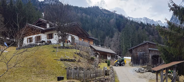 Häuser und ein Traktor in einem Alpendorf nahe der Berge