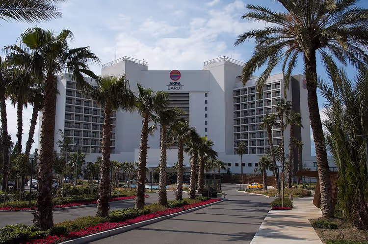 Den hvite bygningen til Akra Barut Hotel blant palmer