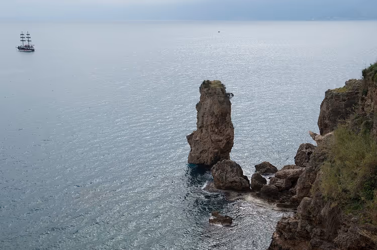 Yelkenli bir tekneyle Antalya'nın kayalık kıyısı