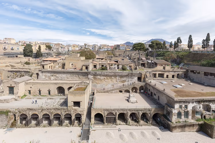 De gamle romerske ruinene av Herculaneum med buer og byen i bakgrunnen