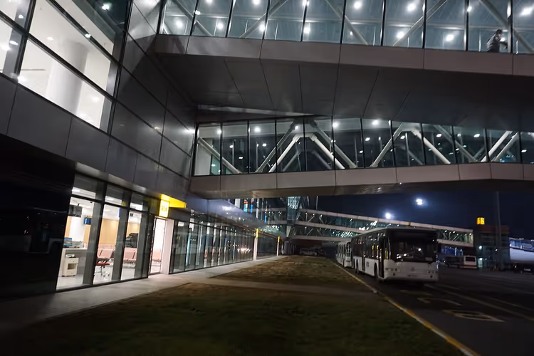 Terminal do Aeroporto de Tbilisi à noite e um autocarro à saída