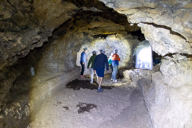 Bir lav mağarasının içinde kask takan turistler