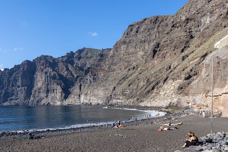 Svart sandstrand og klipper ved Los Gigantes
