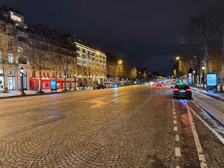 Pariser Straße bei Nacht mit Kopfsteinpflaster und Straßenlaternen