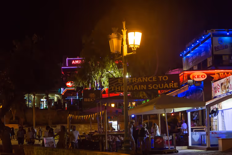 Straße in Ayia Napa bei Nacht mit Neon-Bar-Schildern