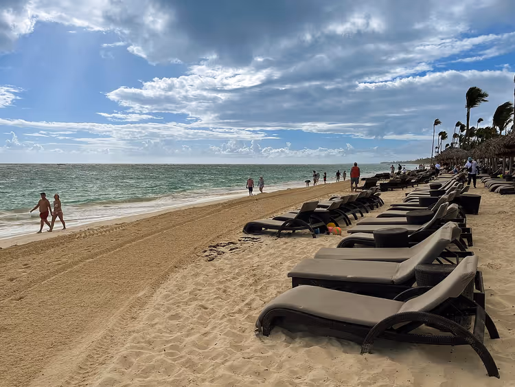 Okyanus kenarında şezlonglar ve palmiyelerle Bavaro Plajı
