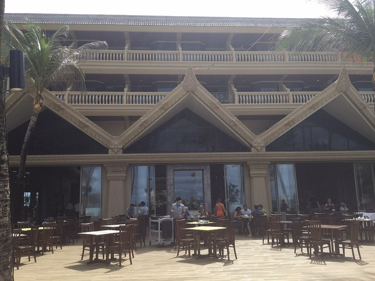 Hotellbygg med thailandske gavler og en restaurantterrasse