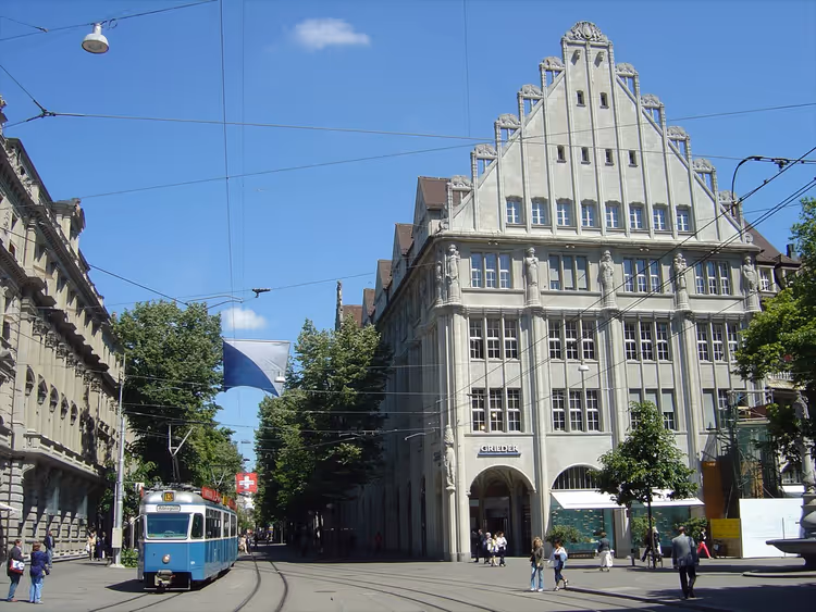 Tramvaylı ve basamaklı alınlıklı bir binanın bulunduğu Bahnhofstrasse