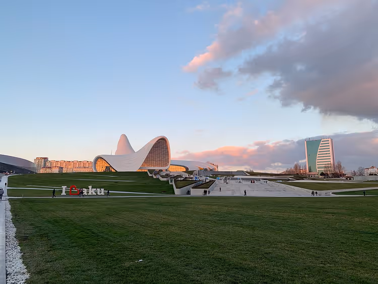 Golvend wit gebouw van het Heydar Aliyev Centrum in Bakoe bij zonsondergang