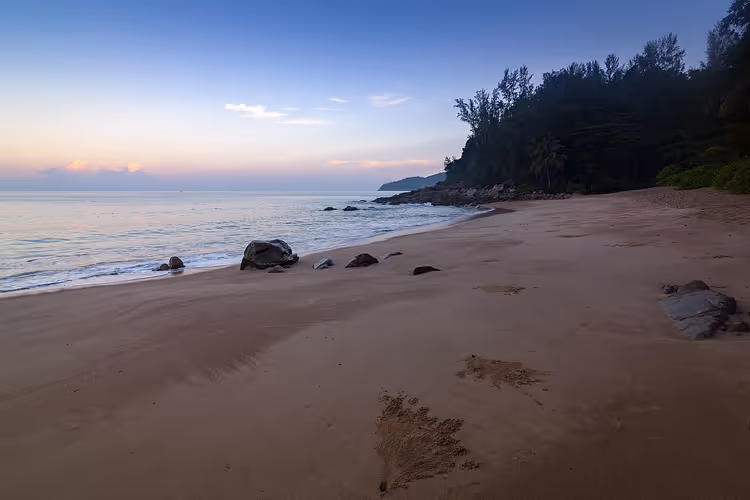 Phuket-strand med sand, klipper og skog i skumringen