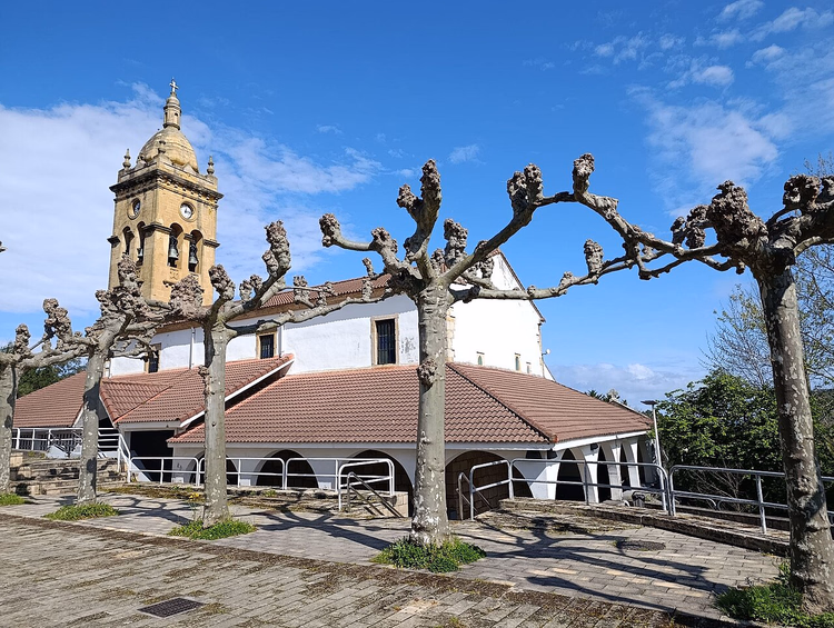 Kerk met een klokkentoren en platanen in Barrika