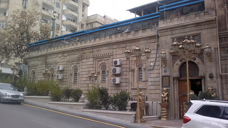 Edificio in pietra con lanterne e un arco su una via di Baku