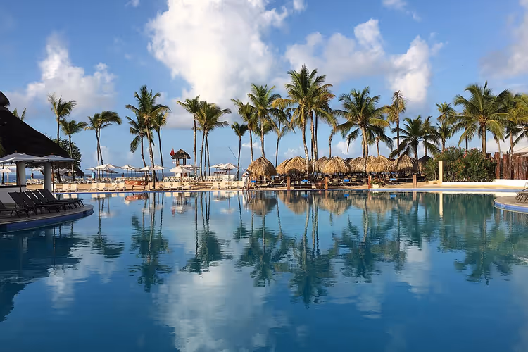 Resortzwembad met palapa's en palmbomen in Bayahibe