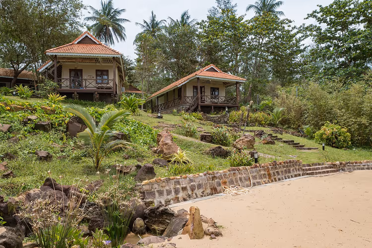 Feriested bungalow på en skråning ved stranden med palmer