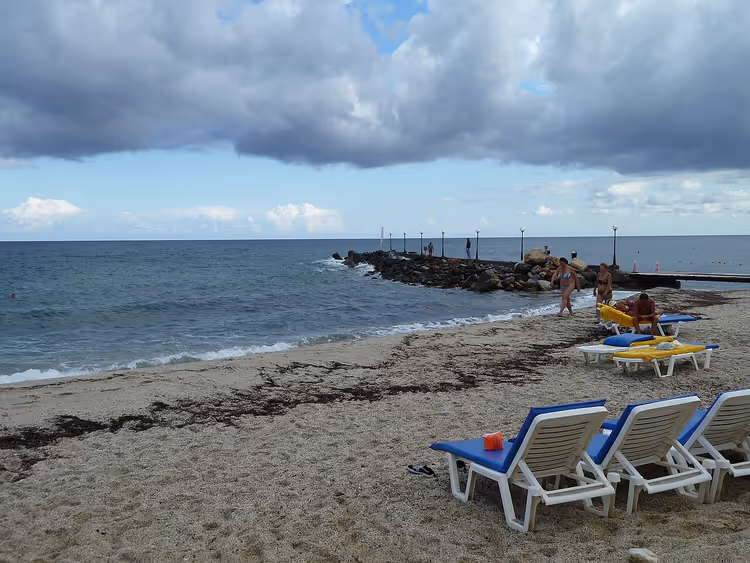 Strand med solsenger og molo ved havet