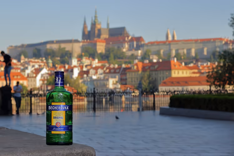 Fles Becherovka met Praag op de achtergrond