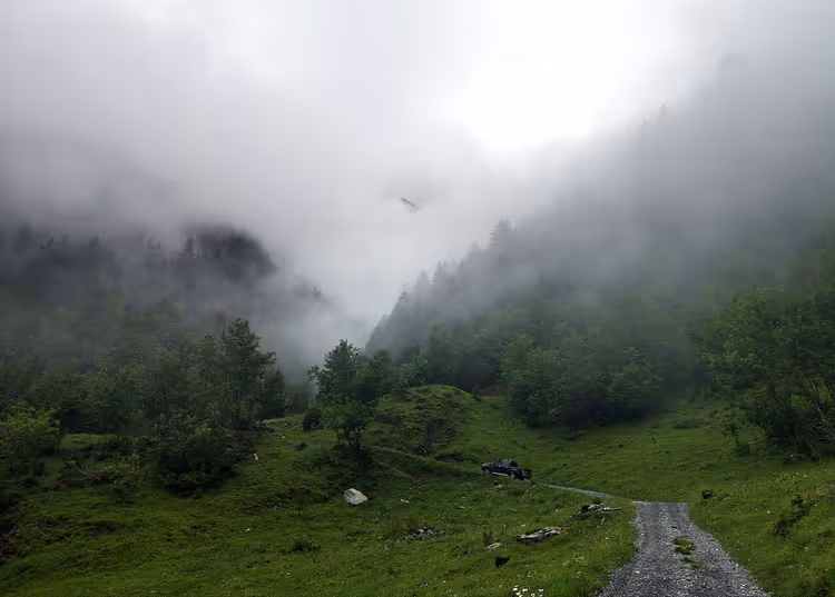 Bil på en fjellvei i de tåkete Alpene